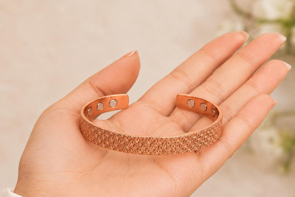 A rose gold open cuff bracelet with a textured honeycomb pattern, held in a person's hand.