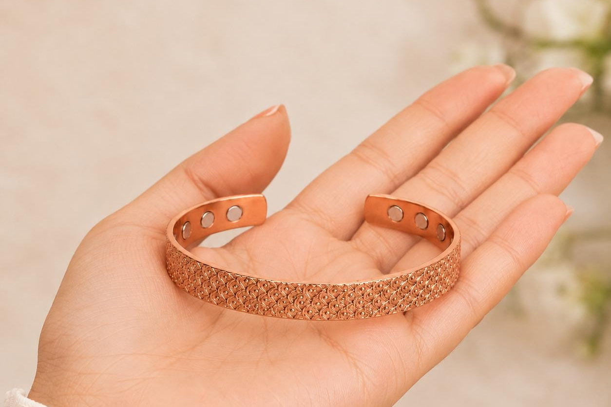 A rose gold open cuff bracelet with a textured honeycomb pattern, held in a person's hand.
