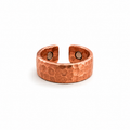 A hammered copper-toned open cuff ring with two circular magnetic inserts, shown on a plain white background.